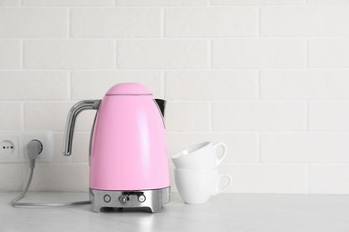 Modern electric kettle and cups on counter in kitchen