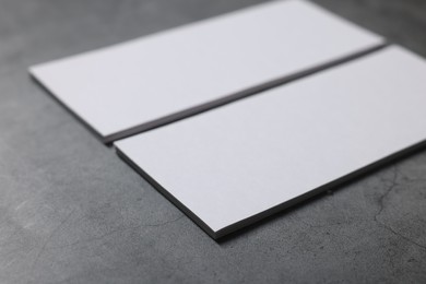 Blank business cards on grey textured table, closeup. Mockup for design