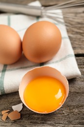 Photo of Raw chicken eggs and shell with yolk on wooden table, closeup. Space for text