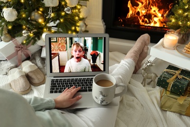 Photo of MYKOLAIV, UKRAINE - DECEMBER 23, 2020: Woman with sweet drink watching Home Alone movie on laptop at home, closeup. Cozy winter holidays atmosphere