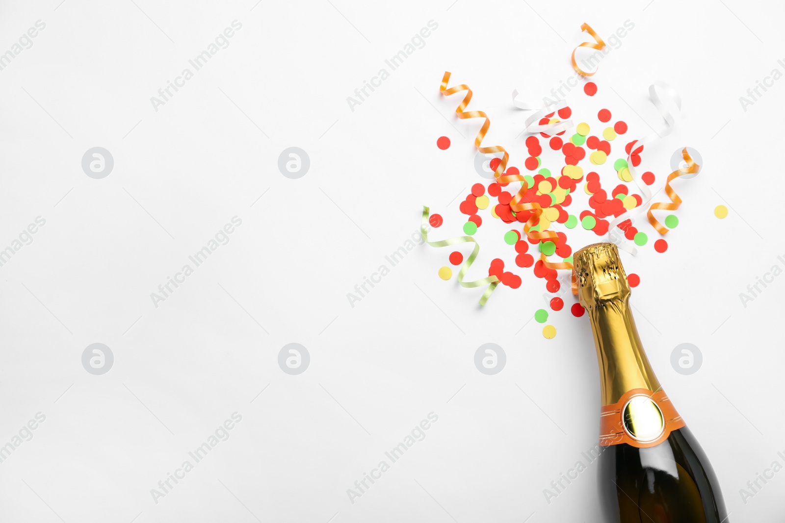 Photo of Flat lay composition with confetti and bottle of champagne on white background. Space for text