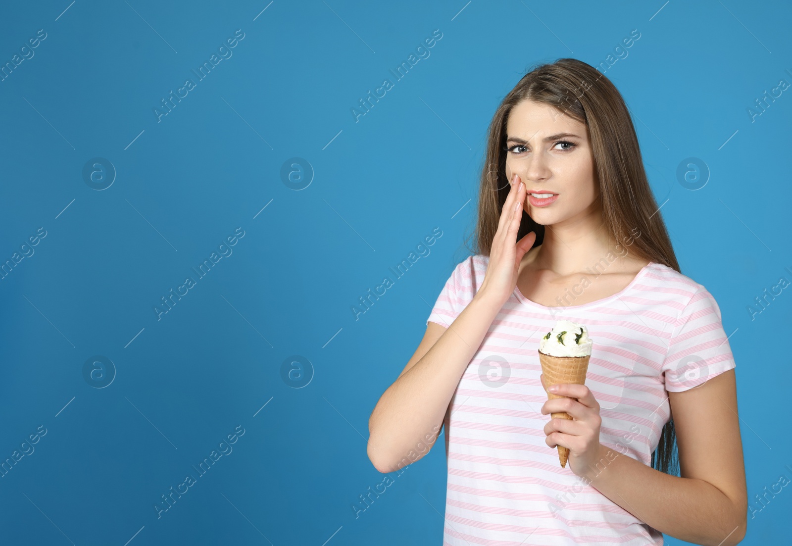 Photo of Emotional young woman with sensitive teeth and ice cream on color background. Space for text