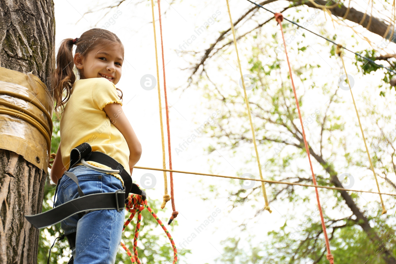 Photo of Little girl climbing in adventure park, space for text. Summer camp