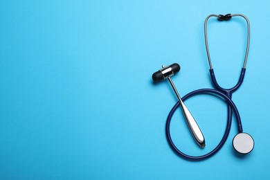 Photo of Reflex hammer, stethoscope and space for text on light blue background, flat lay. Nervous system diagnostic