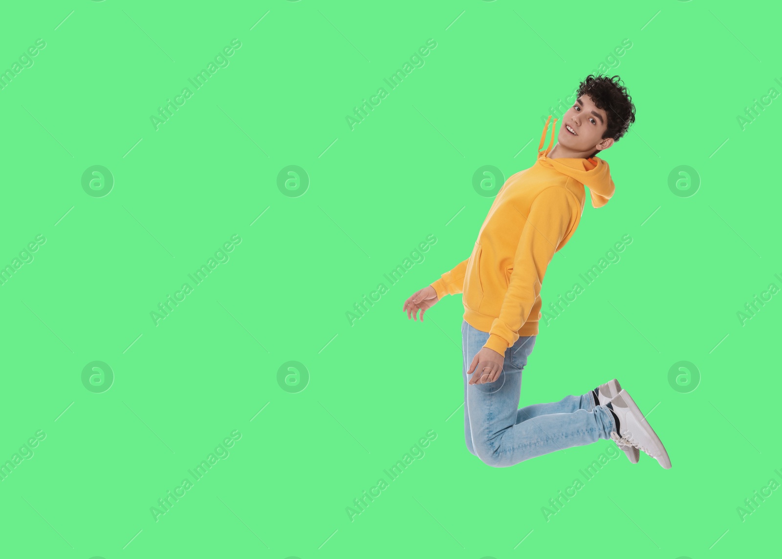 Image of Teenage boy jumping on green background, space for text