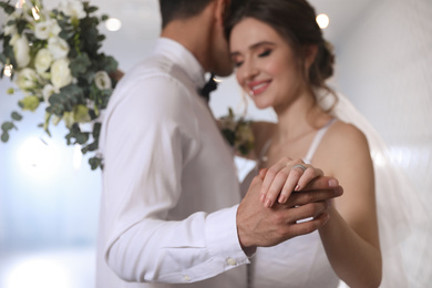 Photo of Happy newlywed couple dancing together in festive hall, focus on hands
