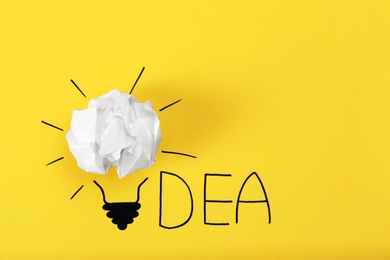 Composition with crumpled paper ball, drawing of lamp bulb and word IDEA on color background. Creative concept