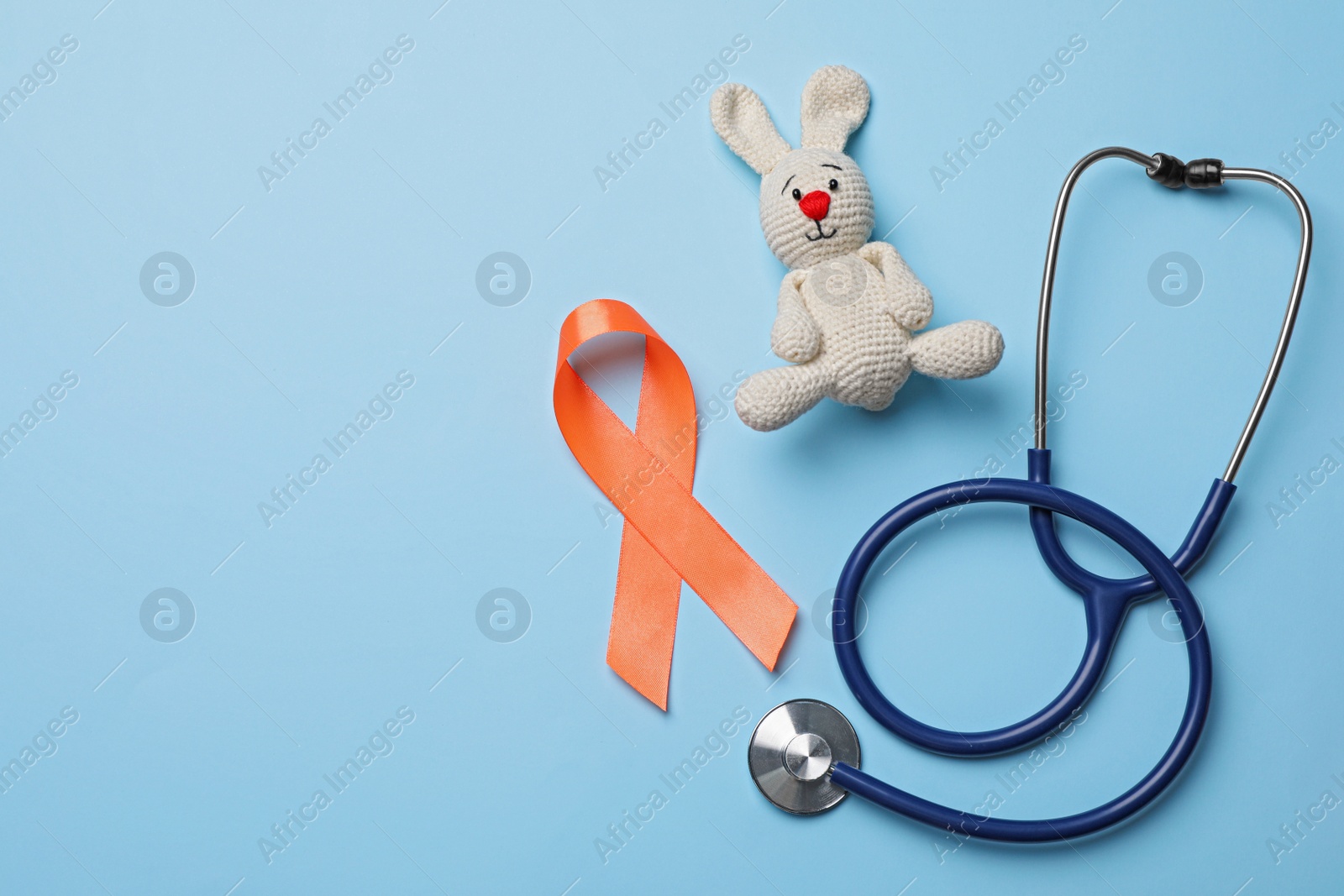 Photo of Orange ribbon, toy bunny and stethoscope on light blue background, flat lay with space for text. Multiple sclerosis awareness