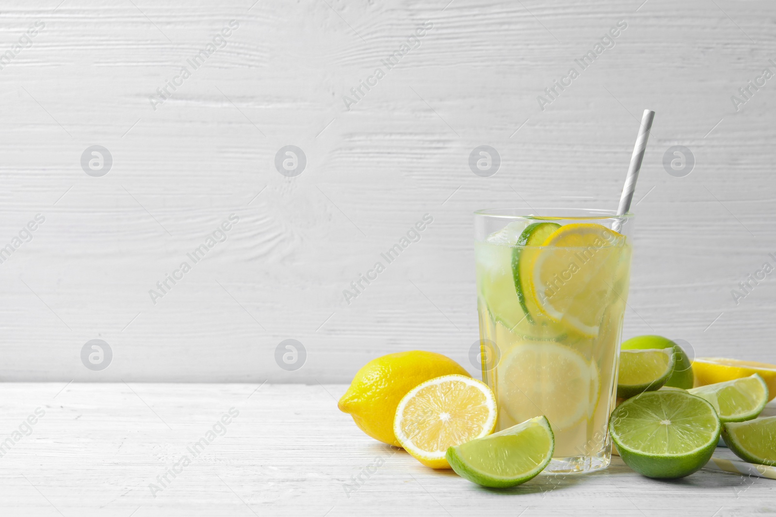 Photo of Glass of natural lemonade with citrus fruits on table