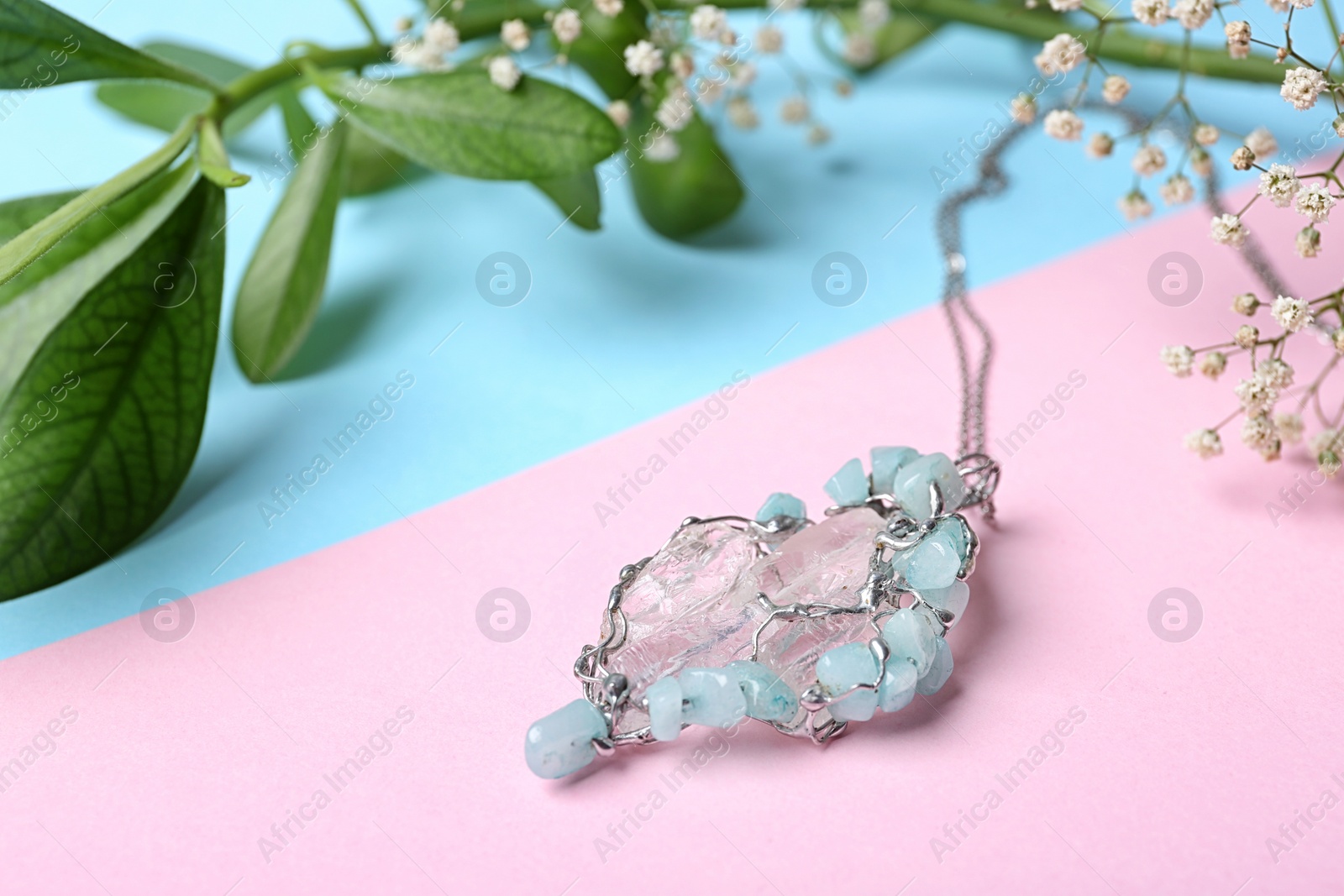 Photo of Beautiful silver pendent with pure quartz gemstones and flowers on color background