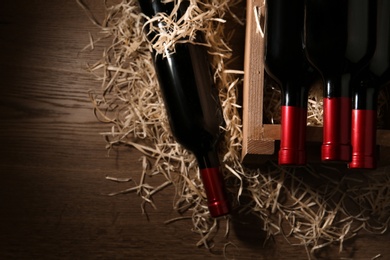 Photo of Flat lay composition with crate and bottles of wine on wooden table