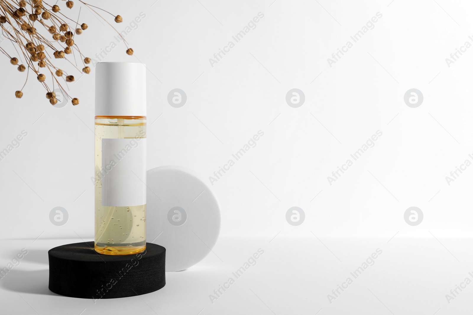 Photo of Bottle of cosmetic product, dried flowers and round podiums on white background, space for text