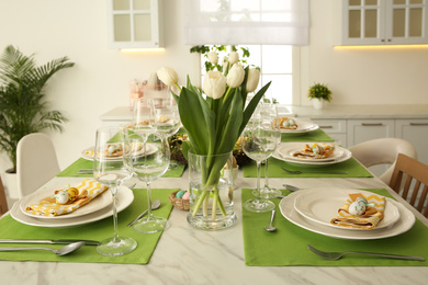 Photo of Festive Easter table setting with floral decor in kitchen