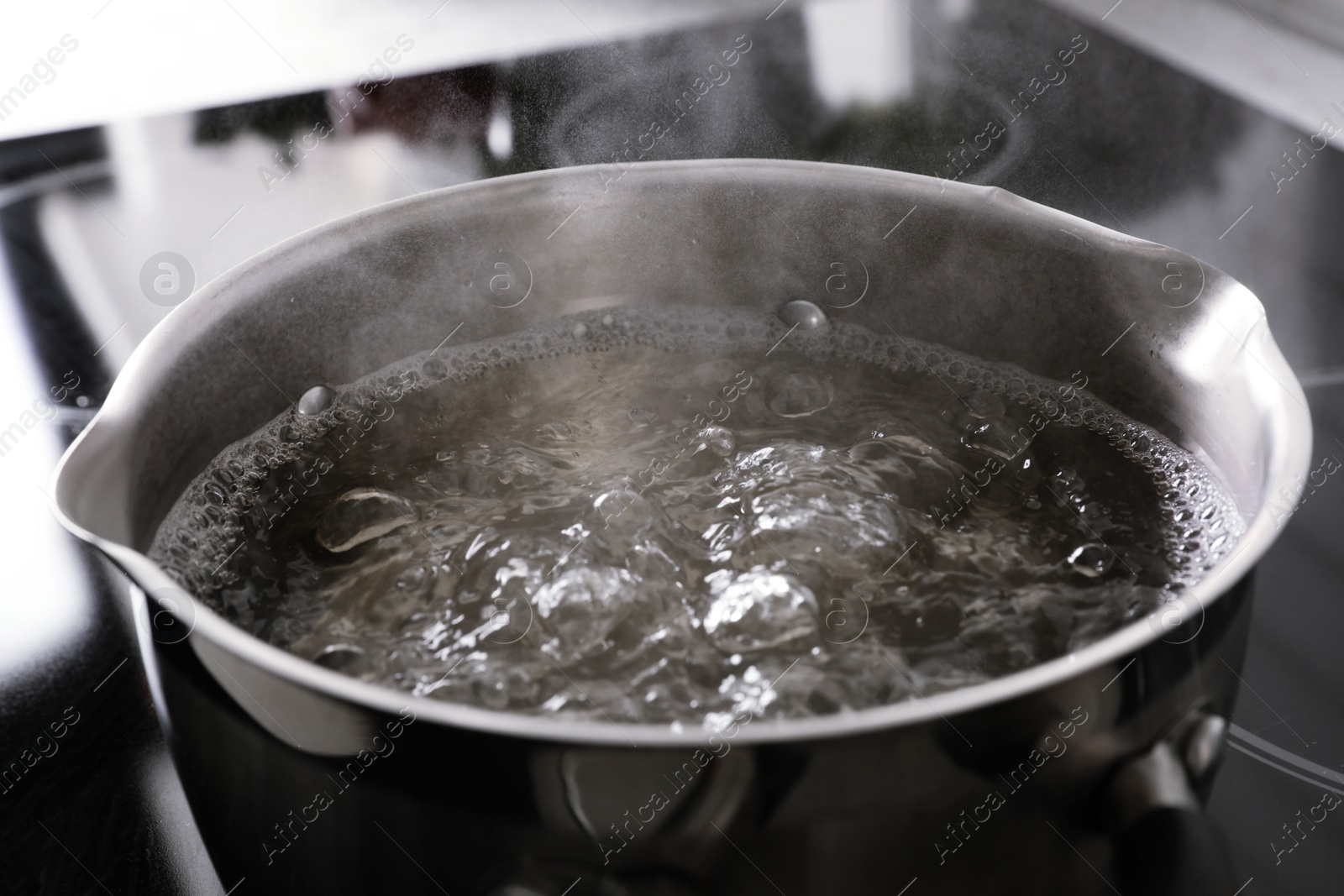 Photo of Pot with boiling water on stove, closeup
