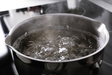 Photo of Pot with boiling water on stove, closeup