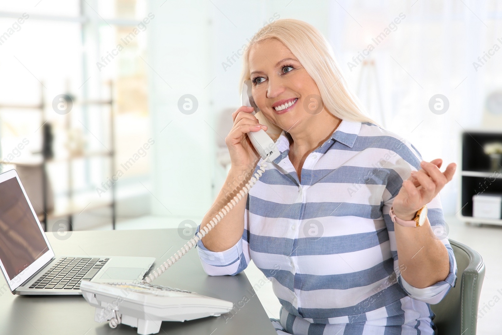 Photo of Mature woman talking on phone at workplace