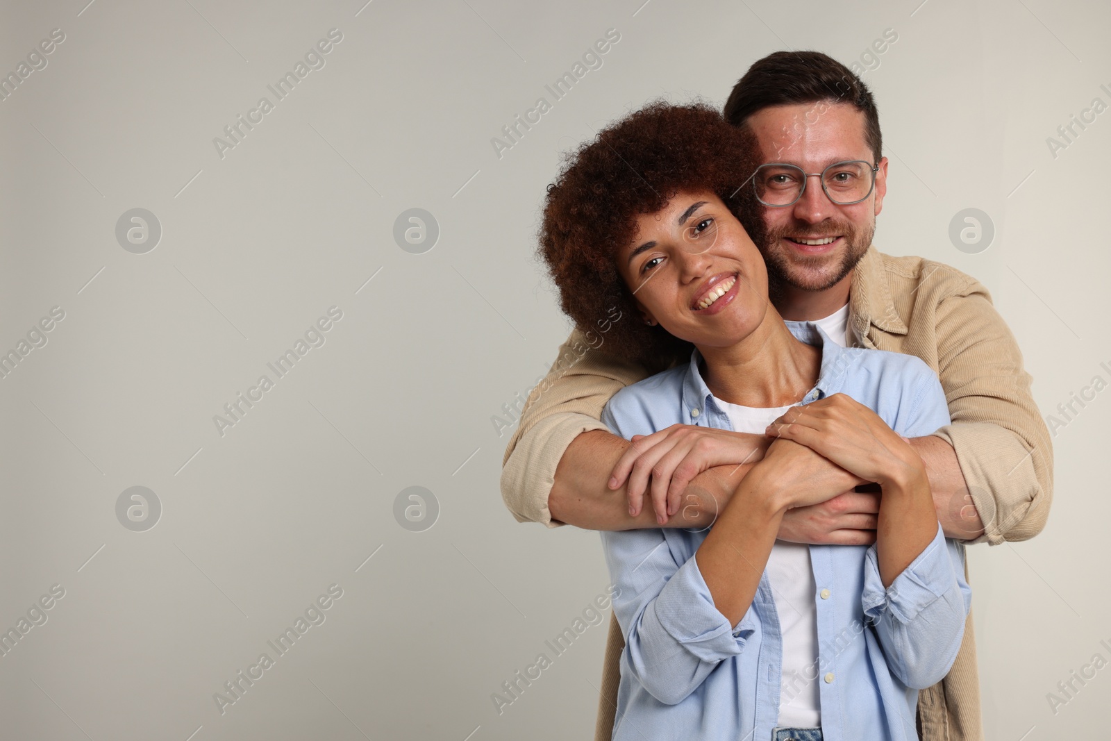Photo of International dating. Happy couple hugging on light grey background, space for text