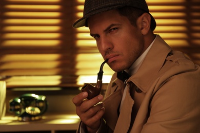 Photo of Old fashioned detective with smoking pipe in office