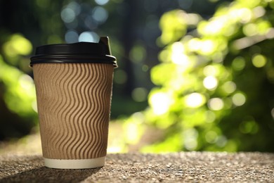 Photo of Cardboard takeaway coffee cup with plastic lid on stone parapet outdoors, space for text