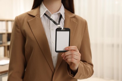 Photo of Woman with blank badge indoors, closeup view