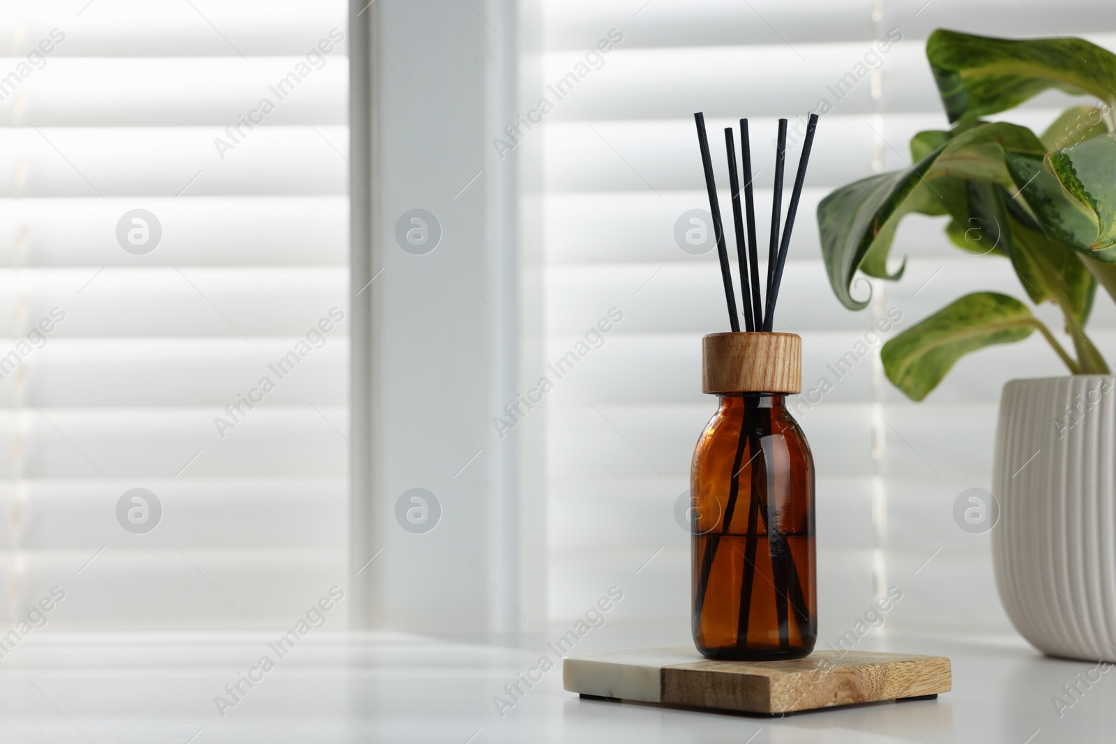 Photo of Air reed freshener and houseplant on white table near window. Space for text