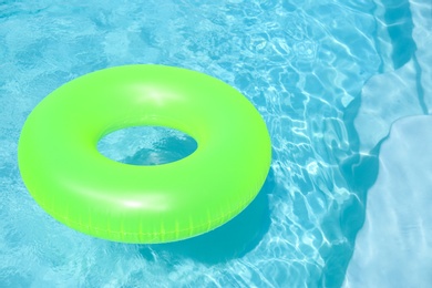 Bright inflatable ring floating in swimming pool on sunny day. Space for text