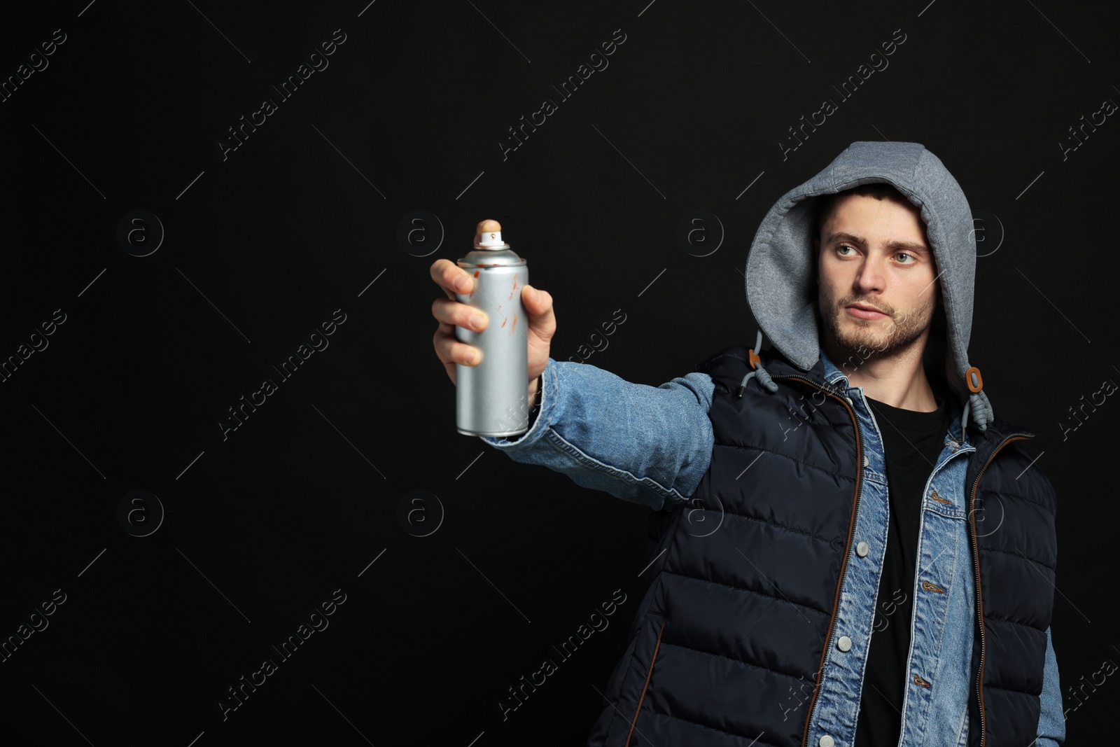 Photo of Handsome man holding used can of spray paint on black background. Space for text