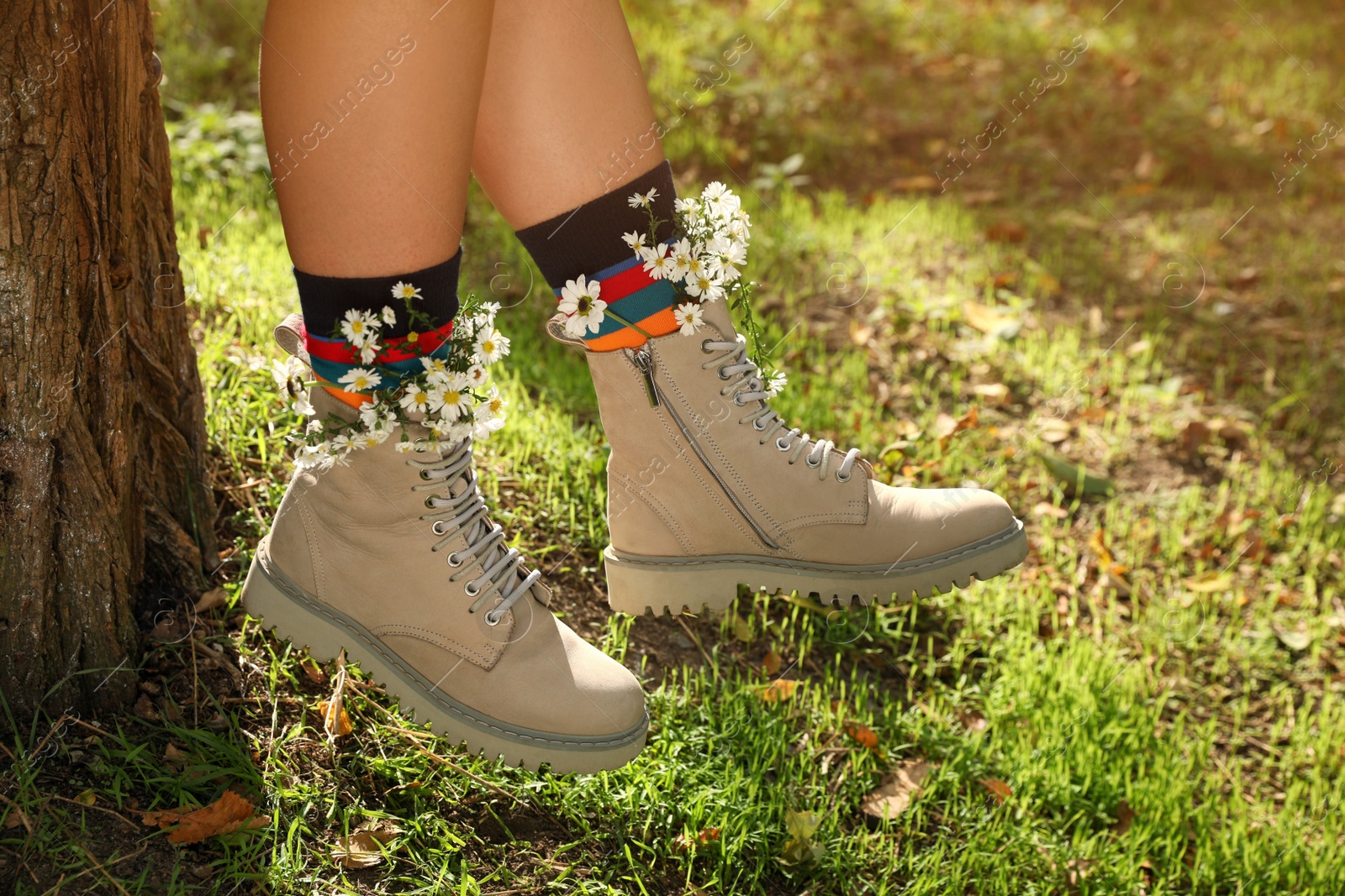 Photo of Woman with beautiful tender flowers in socks outdoors, closeup