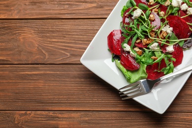 Photo of Plate with delicious beet salad on wooden background, top view