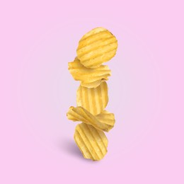 Image of Tasty ridged potato chips falling on pale light violet background