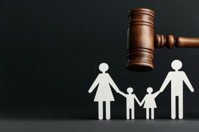 Divorce concept. Paper figures of family and wooden gavel on black background. Space for text