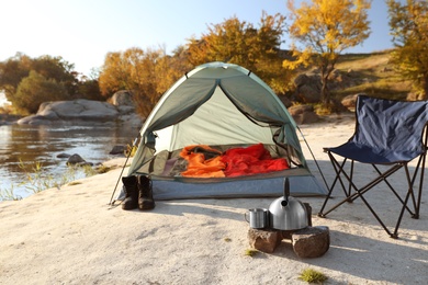 Photo of Camping equipment near tent with sleeping bag outdoors