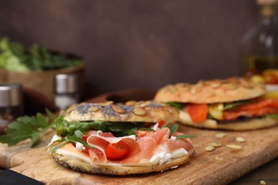 Photo of Wooden board with tasty bagel sandwiches on table, closeup. Space for text