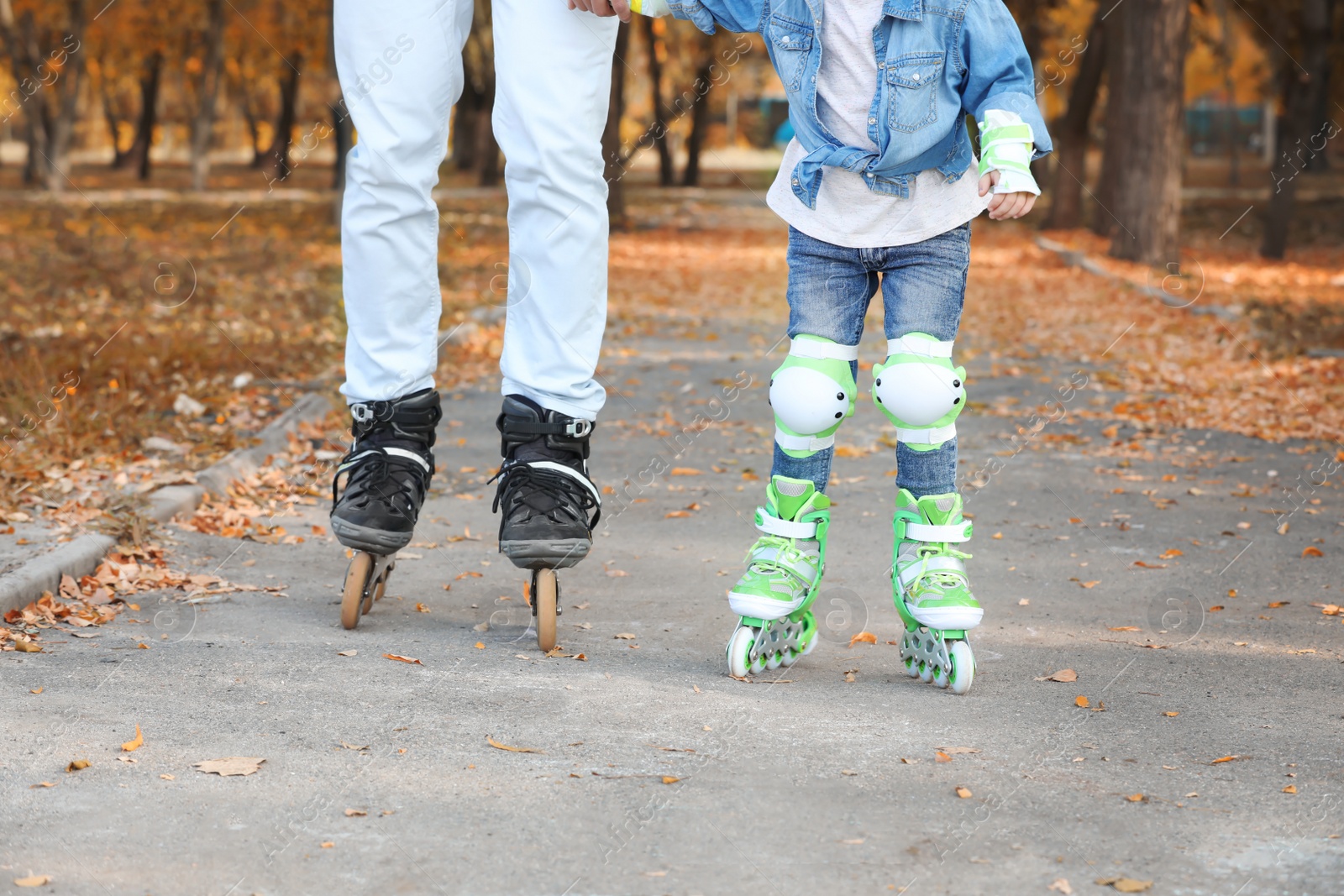 Photo of Father and his daughter roller skating in autumn park