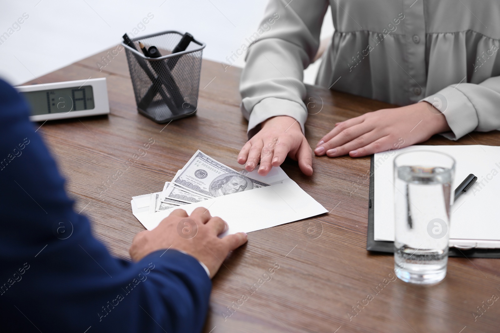 Photo of Man giving bribe money to woman at table, closeup
