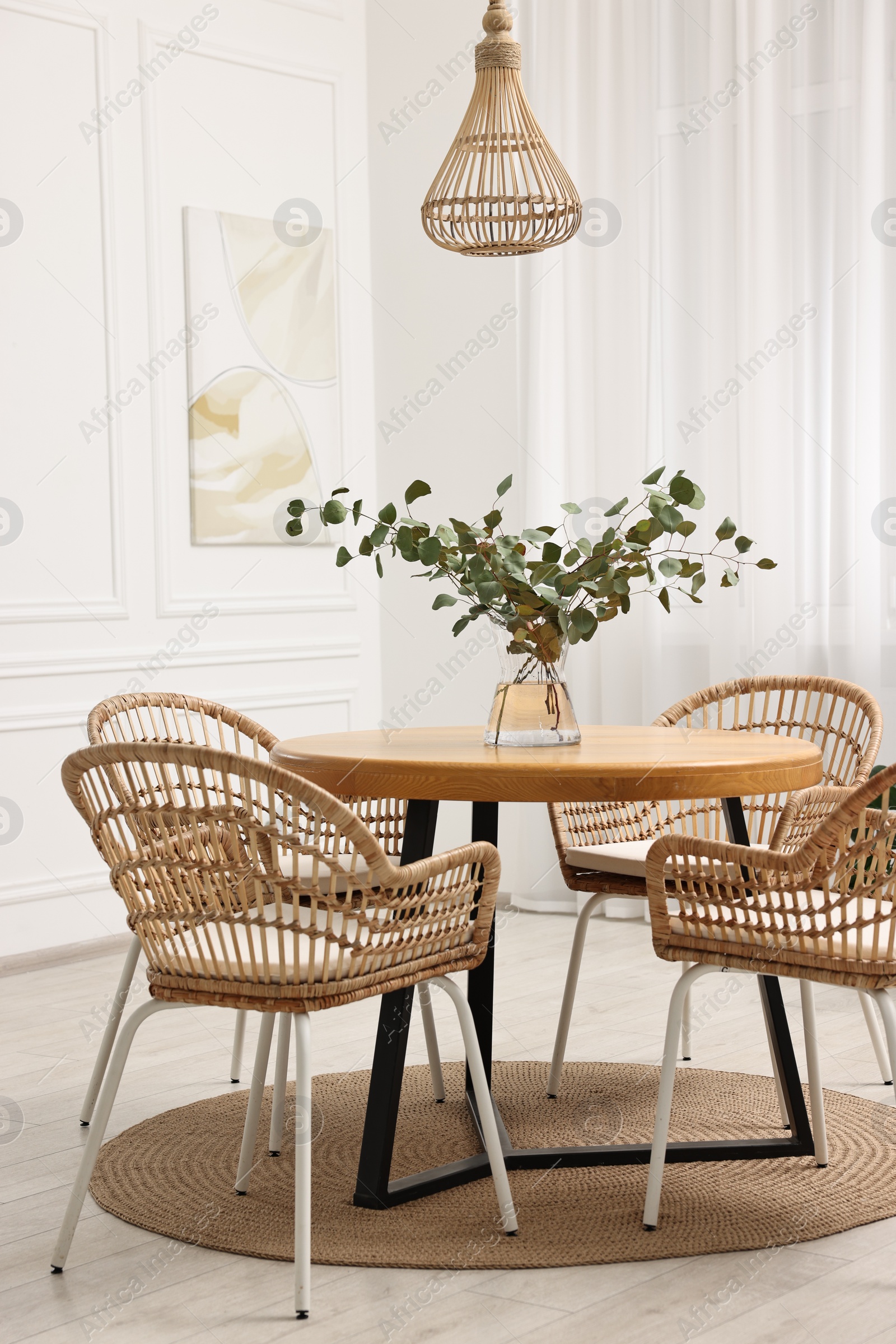 Photo of Dining room interior with comfortable furniture and eucalyptus branches