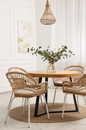 Photo of Dining room interior with comfortable furniture and eucalyptus branches