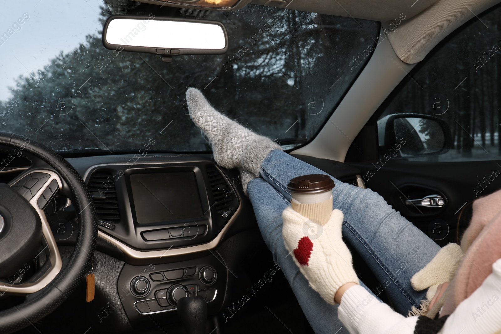 Photo of Woman in warm socks with coffee resting inside car, closeup