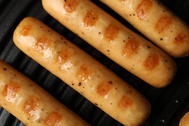 Photo of Delicious vegan sausages cooking on electric grill, top view