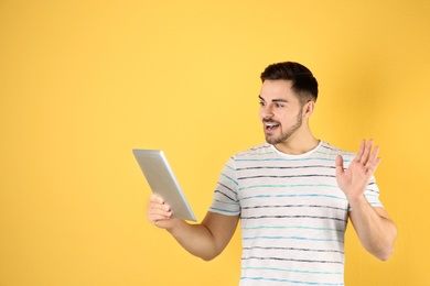 Photo of Man using tablet for video chat on color background. Space for text