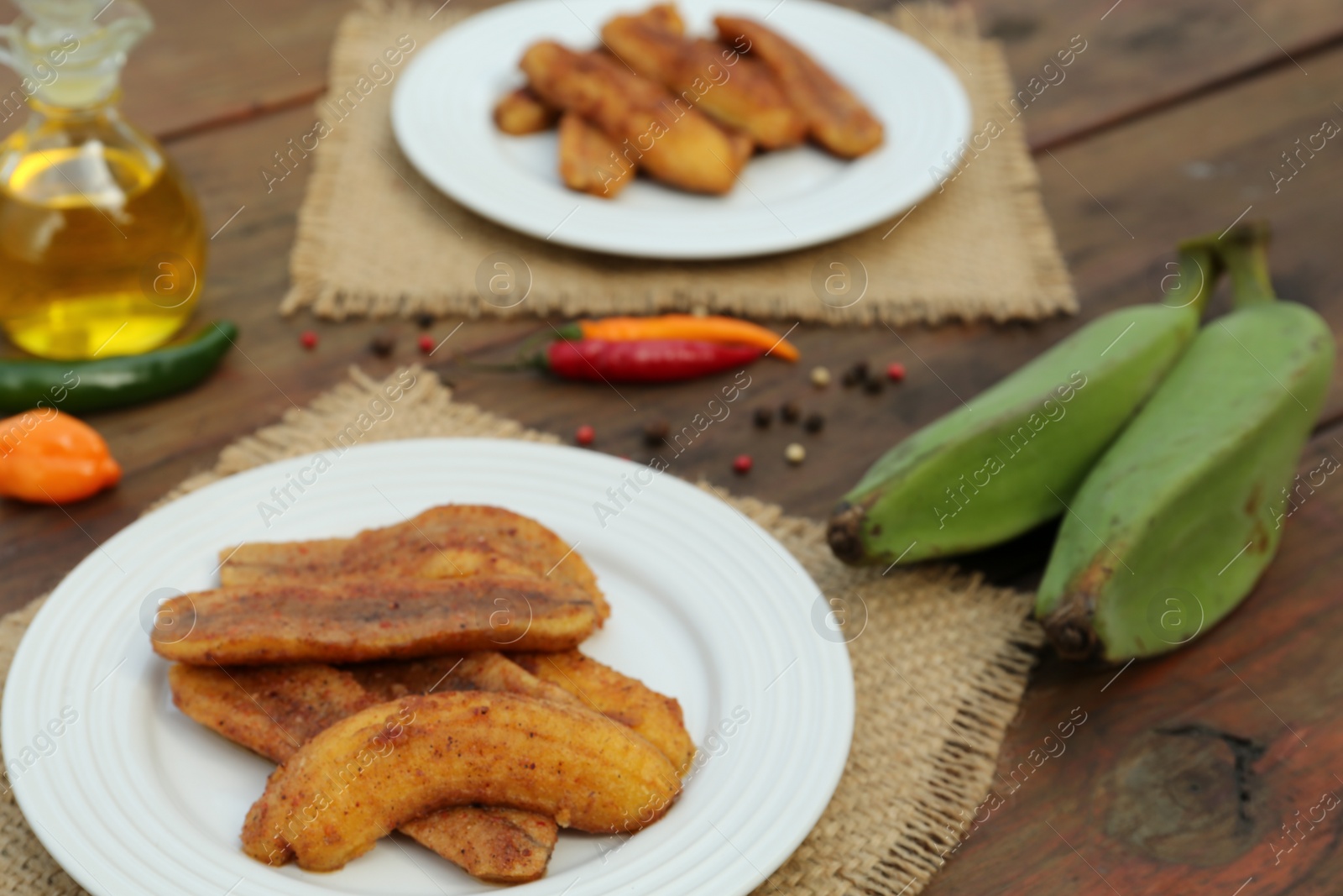 Photo of Delicious fried bananas, fresh fruits and different peppers on wooden table