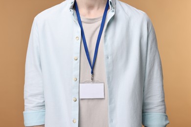 Man with empty badge on beige background, closeup