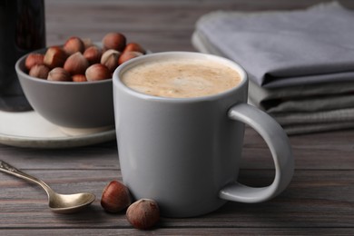 Mug of delicious coffee with hazelnut syrup on wooden table, closeup