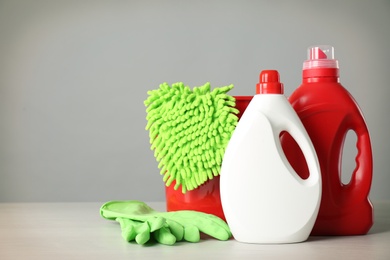 Photo of Bucket and cleaning products on grey table. Space for text