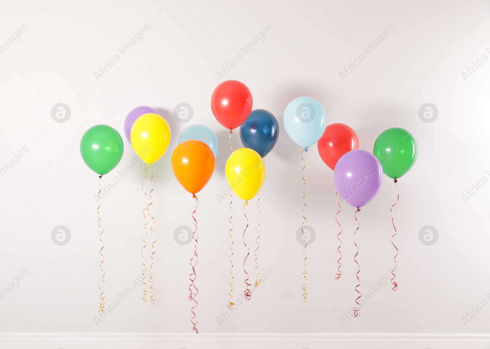 Photo of Different bright balloons against light wall. Celebration time