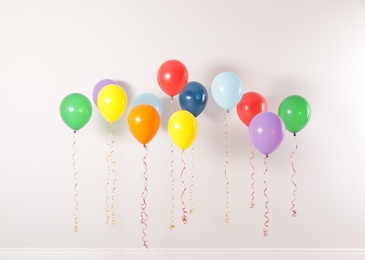 Photo of Different bright balloons against light wall. Celebration time