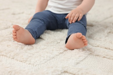 Photo of Baby sitting on soft carpet, closeup view