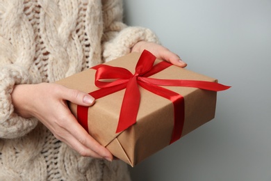 Photo of Woman holding Christmas gift box on grey background, closeup