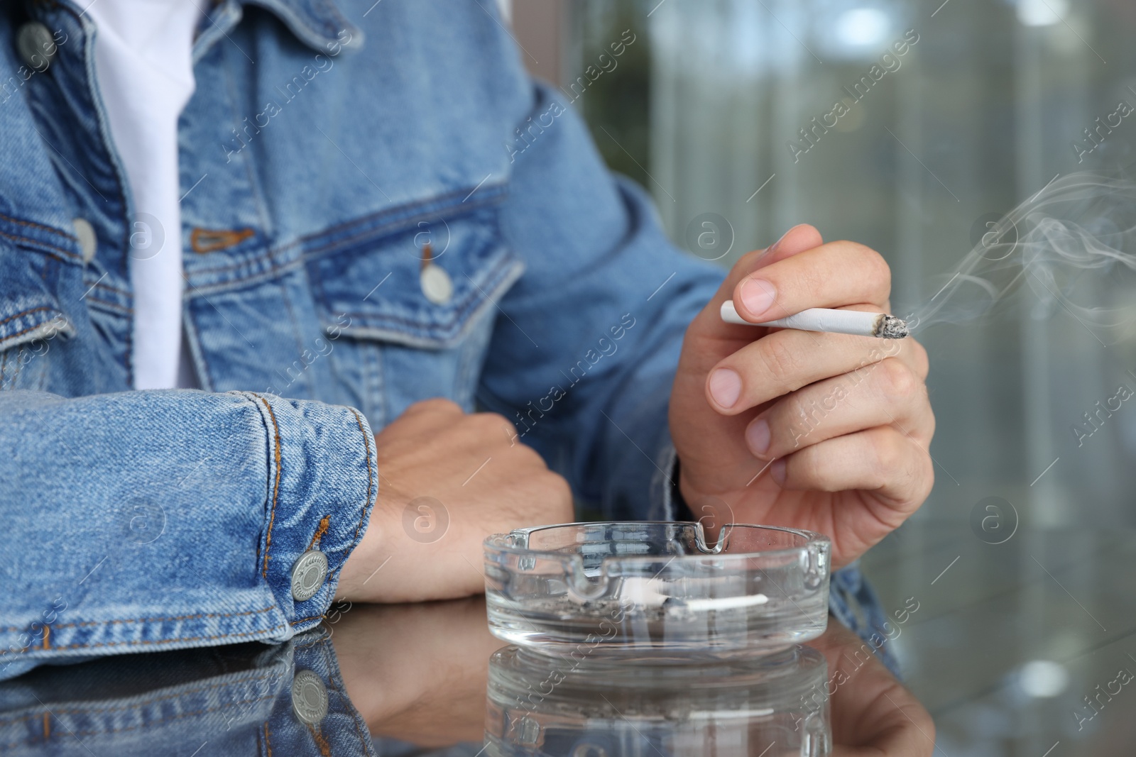 Photo of Man smoking cigarette at table in outdoor cafe, closeup