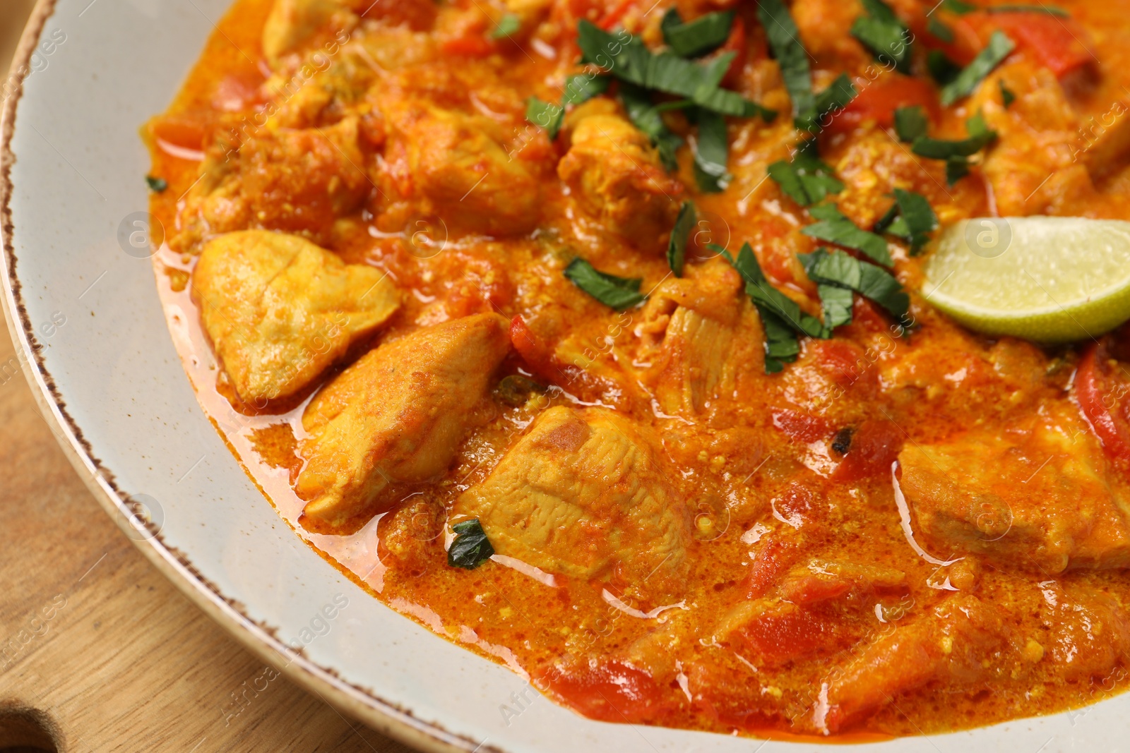 Photo of Delicious chicken curry on wooden board, closeup